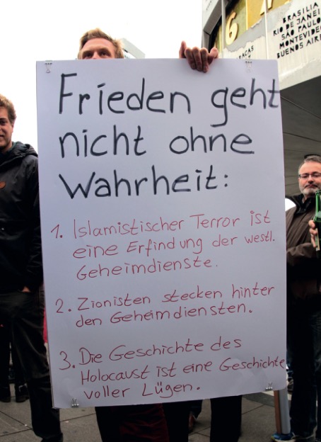 Nikolai Nerling hält auf einer Demonstration ein Schild hoch: »Frieden geht nicht ohne Wahrheit: 1. Islamistischer Terror ist eine Erfindung der westl. Geheindienste. 2. Zionisten stecken hinter den Geheimdiensten. 3. Die Geschichte des Holocaust ist eine Geschichte voller Lügen.«